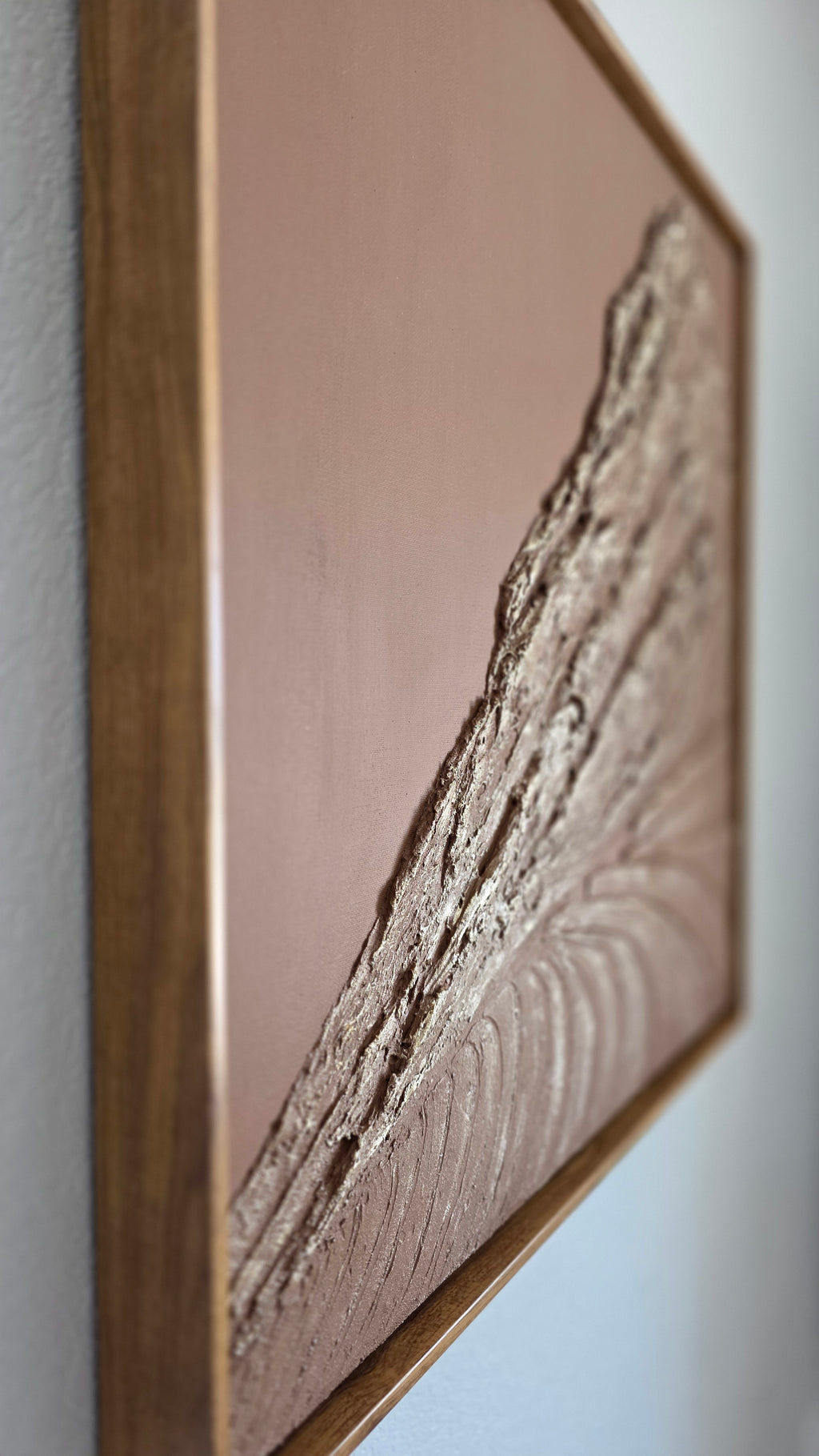 A square framed wall art piece featuring a textured, raised abstract design in metallic silver and gold tones over a warm brown background, set in a medium brown wooden frame.